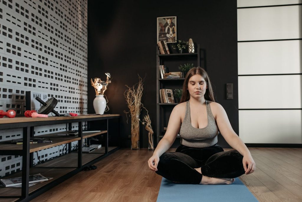 Woman in activewear meditating indoors, promoting wellness and mindfulness.